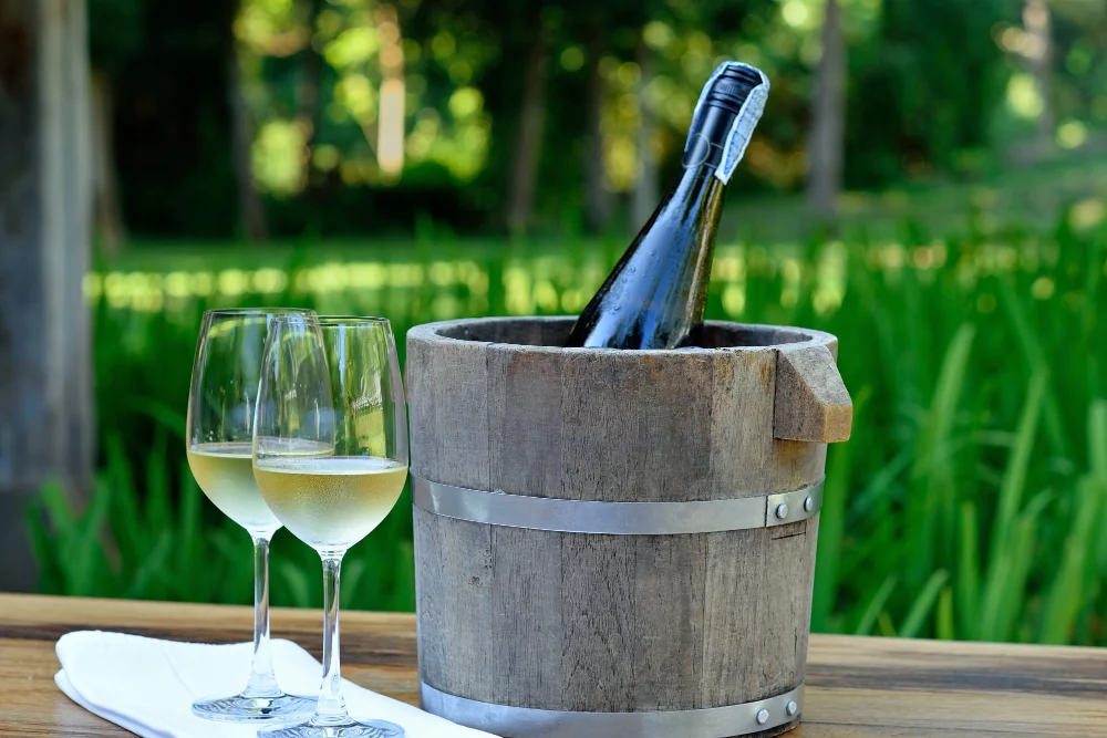 glass white wine wine bottle ice bucket wood table