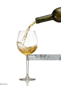 White wine being poured into wine glass on white background