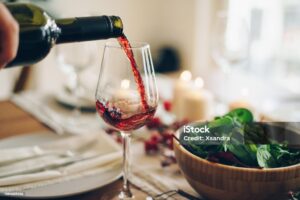 Red wine being poured into the glass at the table