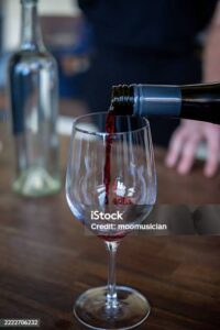 A man is pouring red wine in the glass