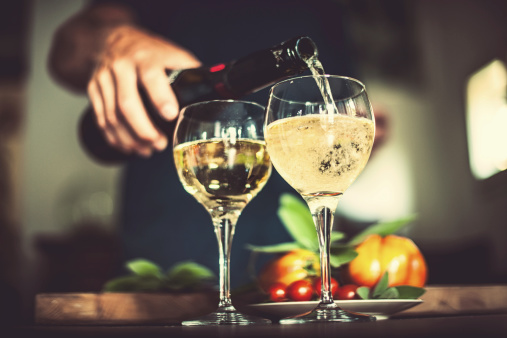 Man pouring prosecco in rustic kitchen