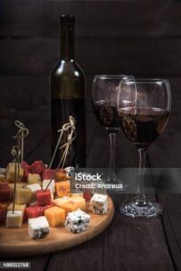 many kinds of cheeses on wooden end of a tree with reed wine